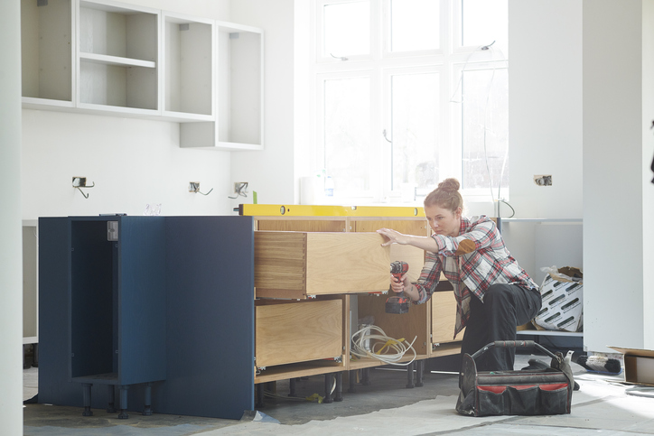 a female kitchen fitter prepping cupboards for worktop