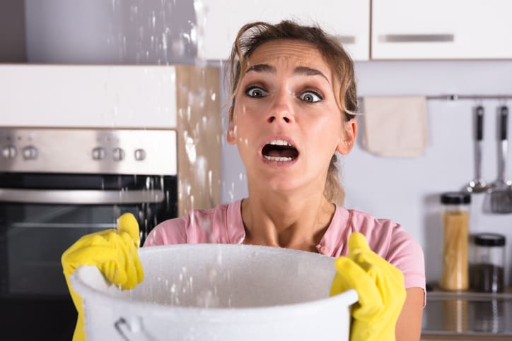 a woman with a bucket collecting leaking water