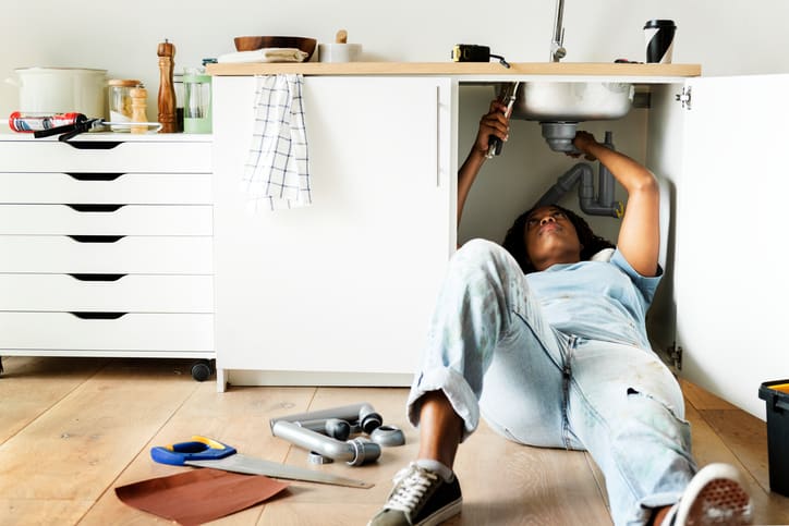 a woman fixing her kitchen sink