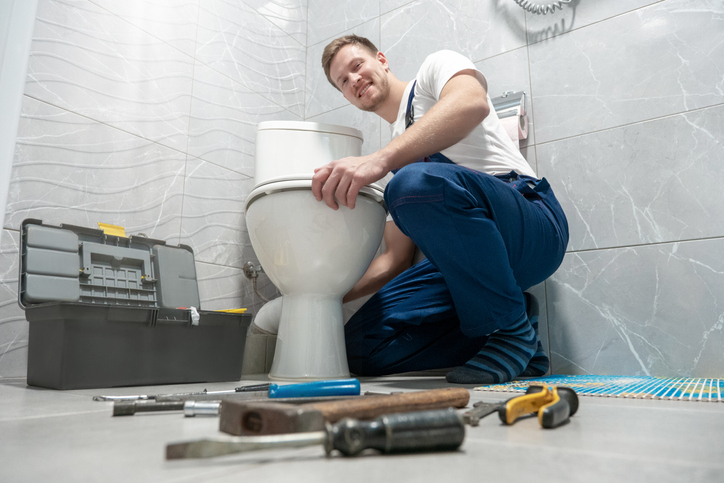 The plumber fixing the toilet with tools in home