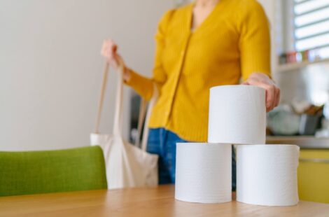 A Woman picking up rolls of toilet paper.