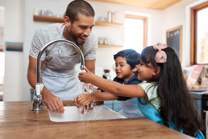 father with boy and girl at the kitchen sink smiling