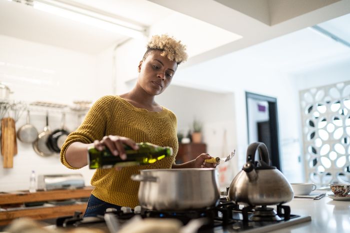 Woman pouring cooking oil into pot in a modern kitchen, WA