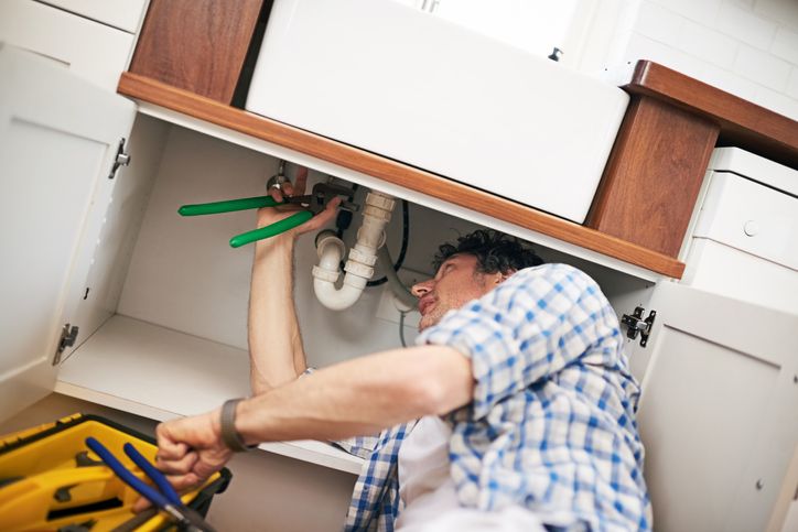 plumber working under sink