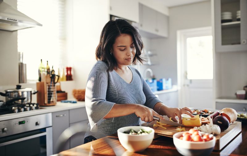 woman cutting vegetables on a board in a modern kitchen