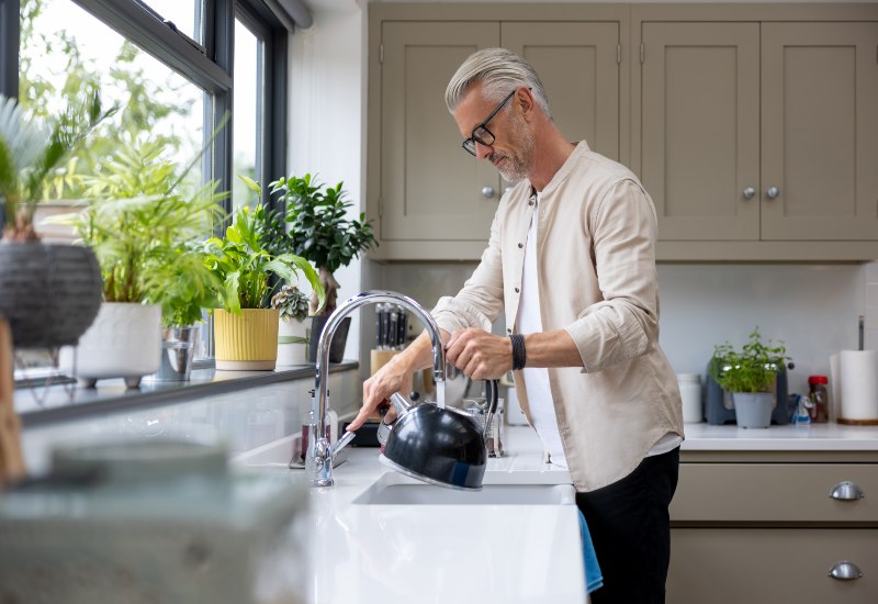 Man preparing to make tea by adding water to kettle