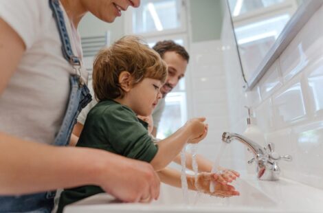 Parents teaching young child how to wash his hands