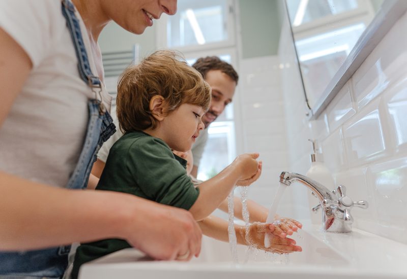 Parents teaching young child how to wash his hands
