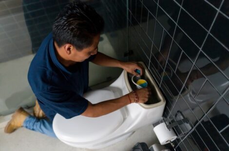 Repairman fixing a toilet bowl in the bathroom