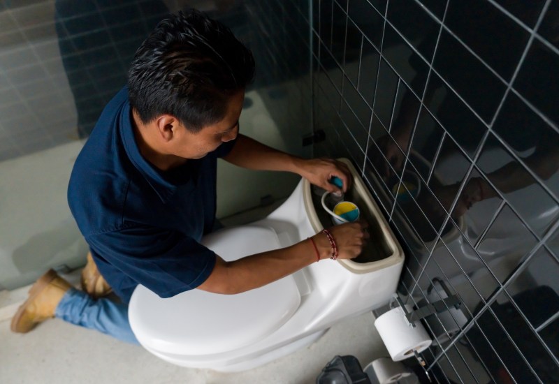 Repairman fixing a toilet bowl in the bathroom