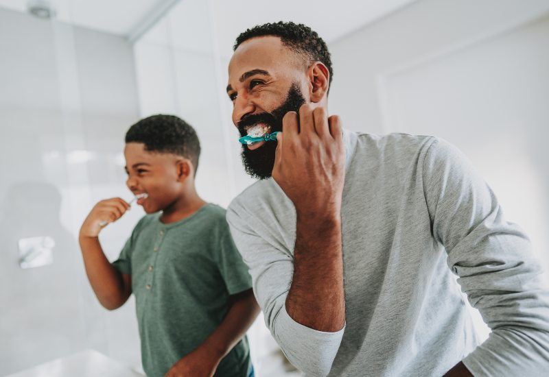 Father and son brushing teeth together