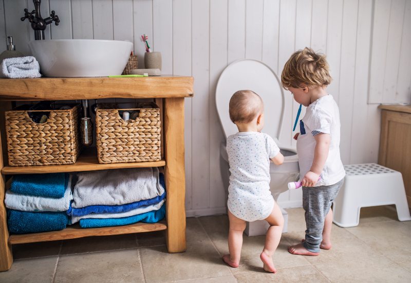 Two toddlers playing around toilet